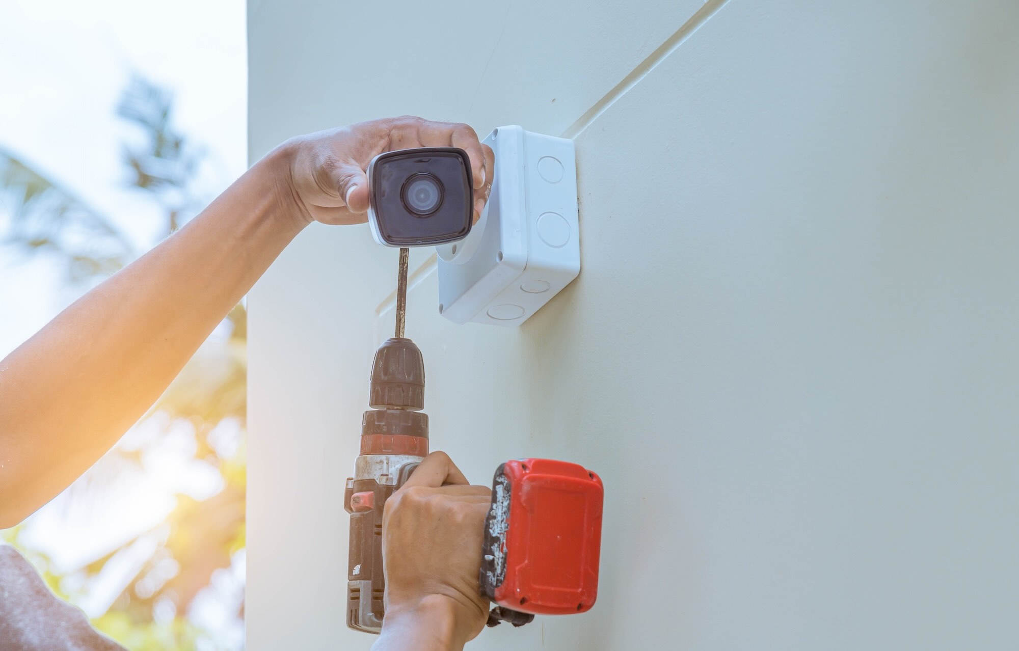 Electrician installing a CCTV camera on the side of a house